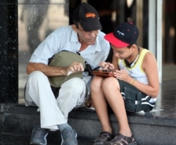 Padre e hijo navegan por la internet en un dispositivo móvil La Habana.